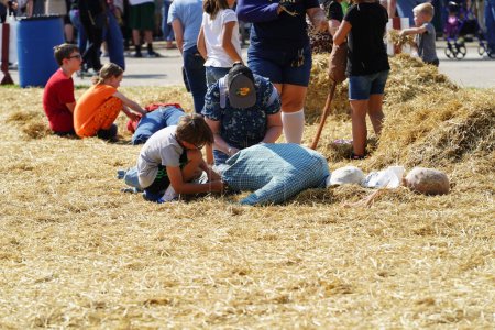 Foto de Milwaukee, Wisconsin, EE.UU. - 30 de septiembre de 2023: Miembros de la familia se reúnen en el festival Wisconsin State Fair for Harvest Fair para crear espantapájaros a partir del heno. - Imagen libre de derechos