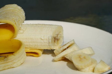 Foto de Banana amarilla pelada y cortada en rodajas se sienta en un plato listo para comer. - Imagen libre de derechos