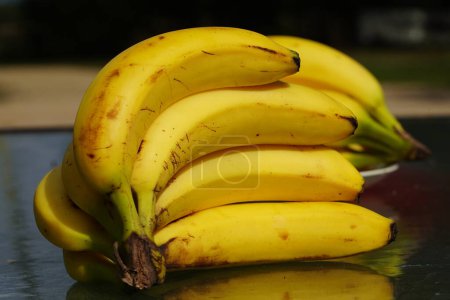 Foto de Un ramo de plátanos maduros se sientan en una mesa afuera listos para ser servidos. - Imagen libre de derechos
