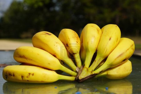 Photo for A bunch of ripe Bananas sit on a table outside ready to be served. - Royalty Free Image