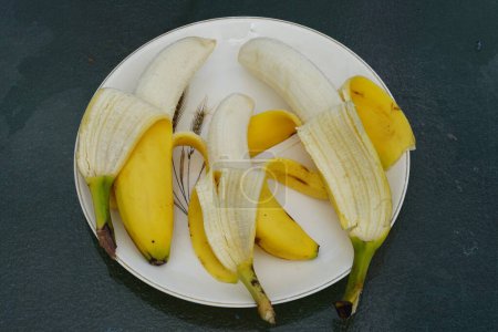 Téléchargez les photos : Banane jaune pelée assise sur une assiette prête à être mangée. - en image libre de droit