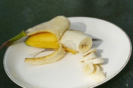 Téléchargez les photos : Banane jaune pelée et tranchée assise sur une assiette prête à être mangée. - en image libre de droit