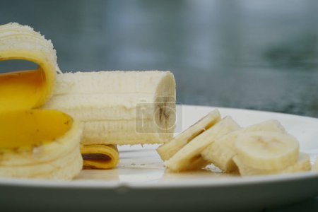 Foto de Banana amarilla pelada y cortada en rodajas se sienta en un plato listo para comer. - Imagen libre de derechos
