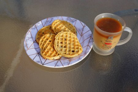 Photo for Glass Christmas coffee mug with coffee and creamer alongside a plate of chocolate chip waffles. - Royalty Free Image