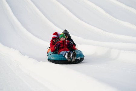 Foto de Kewaskum, Wisconsin / Estados Unidos - 24 de diciembre de 2019: Muchos miembros de la familia salieron a disfrutar de los tubos de nieve el día antes de Navidad en el Sunburst Winter Sports Park para el evento de Santa Slalom. - Imagen libre de derechos