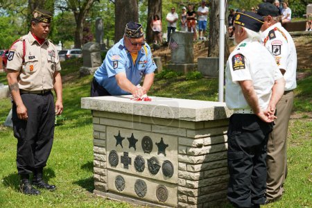 Photo for Oconomowoc, Wisconsin / USA - May 25th, 2020: Veterans and senior officers placing remembrance ribbons of fallen soldiers on the unknown soldier grave at la belle cemetery for honoring memorial day. - Royalty Free Image