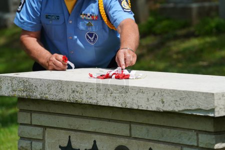 Téléchargez les photos : Oconomowoc, Wisconsin / États-Unis - 25 mai 2020 : Des vétérans et des officiers supérieurs posent des rubans commémoratifs de soldats tombés au combat sur la tombe d'un soldat inconnu au cimetière de la belle pour honorer le jour du Souvenir. - en image libre de droit