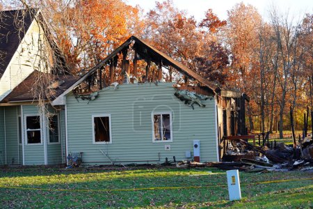 Téléchargez les photos : Une maison incendiée par un incendie dans la campagne près d'une forêt. - en image libre de droit