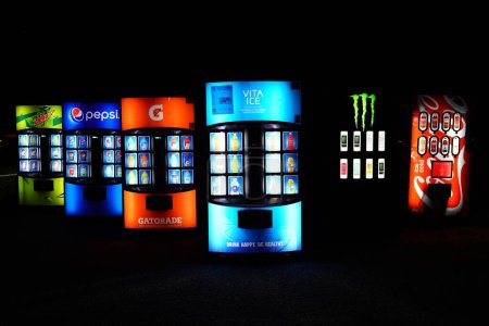 Photo for New Lisbon, Wisconsin USA - November 17th, 2023: Soda and drink dispenser machines sit at the roadside glowing during the night. - Royalty Free Image