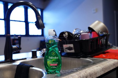 Téléchargez les photos : Fond du Lac, Wisconsin États-Unis - 28 janvier 2024 : Une petite bouteille de savon à vaisselle Palmolive se trouve devant un séchoir à vaisselle dans une cuisine. - en image libre de droit