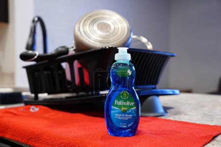 Photo for Fond du Lac, Wisconsin USA - January 28th, 2024: Small bottle of Palmolive dish soap sits in front of a drying rack of dishes in a kitchen. - Royalty Free Image