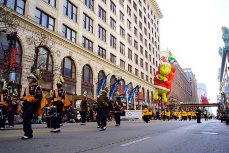 Foto de Chicago, Illinois, Estados Unidos - 23 de noviembre de 2023: Miembros del Desfile del Día de Acción de Gracias de Chicago tiraron del globo del personaje de Grinch a través de State Street. - Imagen libre de derechos