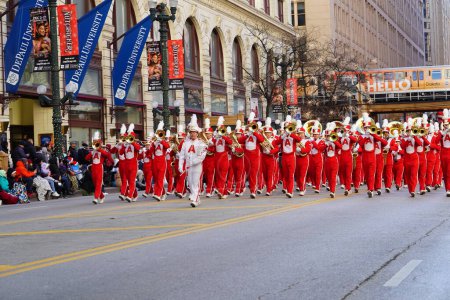 Photo for Chicago, Illinois USA - November 23rd, 2023: Asian high school marching band students of Arcadia marched in red uniforms through State Street during the 2023 Thanksgiving Day Parade. - Royalty Free Image