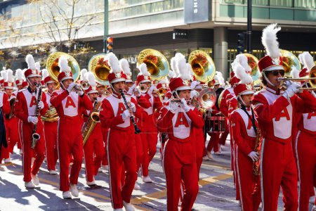Photo for Chicago, Illinois USA - November 23rd, 2023: Asian high school marching band students of Arcadia marched in red uniforms through State Street during the 2023 Thanksgiving Day Parade. - Royalty Free Image