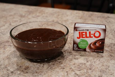Photo for Fond du Lac, Wisconsin USA - February 15th, 2024: A box of Jell-O 3.9 oz Chocolate Fudge instant Pudding mix next to a bowl of Chocolate pudding. - Royalty Free Image