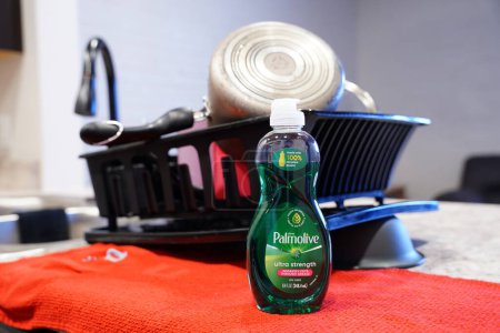 Photo for Fond du Lac, Wisconsin USA - January 28th, 2024: Small bottle of Palmolive dish soap sits in front of a drying rack of dishes in a kitchen. - Royalty Free Image
