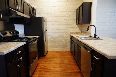 Foto de Fond du Lac, Wisconsin Estados Unidos - 28 de enero de 2024: Toda la cocina de color negro con encimeras blancas en un piso de madera dentro de un apartamento estudio. - Imagen libre de derechos