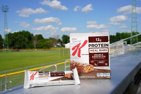 Photo for Beaver dam, Wisconsin / USA - June 27th, 2020: Special K Protein Meal Bar, Double Chocolate 6 pack, 1.59 oz bars 5 grams of fiber and 12 minerals and vitamins sits on bench at football field. - Royalty Free Image