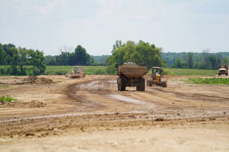 Foto de Fond du Lac, Wisconsin / Estados Unidos - 14 de julio de 2020: Caterpillar 735 camiones volquete de construcción que transportan material de suciedad para construir la tierra a una carretera de expansión 23 desde el aficionado du lac al sheboygan. - Imagen libre de derechos
