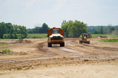 Photo for Fond du Lac, Wisconsin / USA - July 14th, 2020: Caterpillar 735 construction dump trucks carrying dirt material to construct the land to a expan highway 23 from fond du lac to sheboygan. - Royalty Free Image
