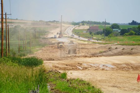 Foto de Fond du Lac, Wisconsin / Estados Unidos - 14 de julio de 2020: Caterpillar 735 camiones volquete de construcción que transportan material de suciedad para construir la tierra a una carretera de expansión 23 desde el aficionado du lac al sheboygan. - Imagen libre de derechos