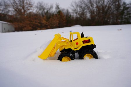 Téléchargez les photos : Jouet de construction de chargeuse frontale jaune pour enfants s'assoit dans la neige pendant la saison d'hiver. - en image libre de droit