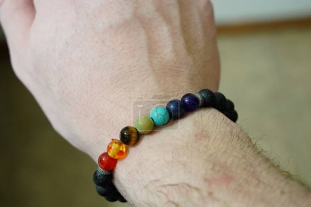 Téléchargez les photos : Bracelet en perles de chakra de roche de lave au poignet d'un homme - en image libre de droit