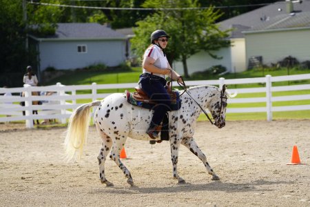 Photo for Fond du Lac, Wisconsin / USA - July 17th, 2019: Young girl riding around on her horse on a public horse ranch field in Fond du Lac, Wisconsin - Royalty Free Image