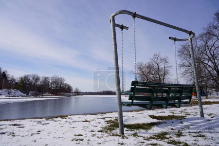 Téléchargez les photos : La balançoire de banc vert se trouve en face du lac Green, Wisconsin pendant la saison d'hiver. - en image libre de droit