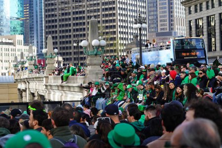 Foto de Chicago, Illinois, EE.UU. - 16 de marzo de 2024: Los espectadores vestidos con colores y trajes de San Patricio se pararon y observaron el teñido de color verde del río Chicago frente al edificio Trump. - Imagen libre de derechos