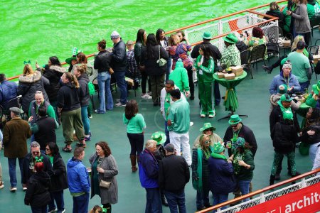 Téléchargez les photos : Chicago, Illinois États-Unis - 16 mars 2024 : Des spectateurs vêtus de couleurs et de costumes de St. Patrick se tenaient debout et regardaient la teinture en couleur verte de la rivière Chicago. - en image libre de droit