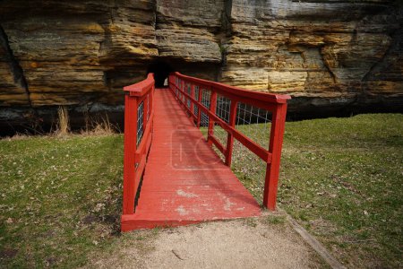 A red man-made bridge leads into a rock tunnel at Pier County Park in Rockbridge, Wisconsin a Native American historical site.