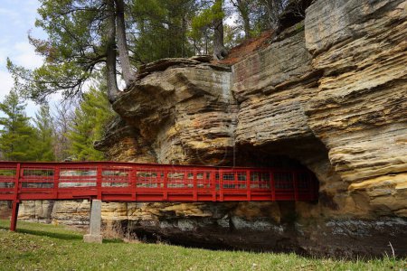 A red man-made bridge leads into a rock tunnel at Pier County Park in Rockbridge, Wisconsin a Native American historical site.