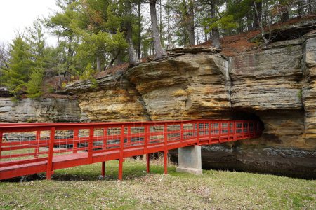 Eine rote künstliche Brücke führt in einen Felstunnel am Pier County Park in Rockbridge, Wisconsin, einer historischen Stätte der Ureinwohner Amerikas.