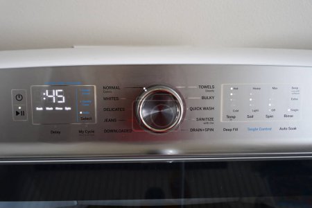 Washing machine dials, controls and settings on a metal panel.
