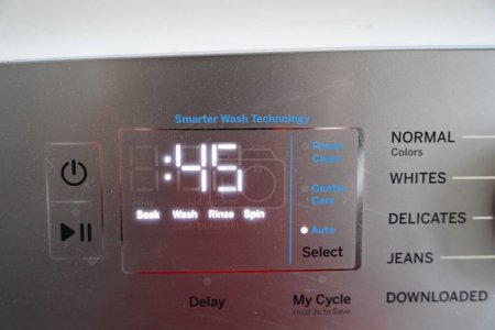 Washing machine dials, controls and settings on a metal panel.