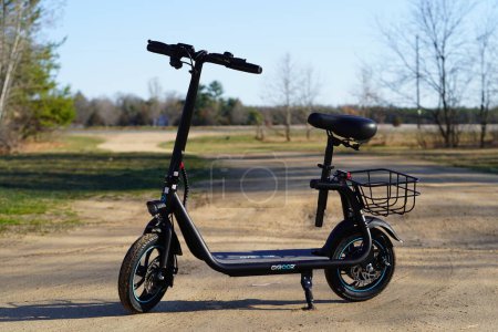 Photo for New Lisbon, Wisconsin USA - April 13th, 2024: A Gyroor electric scooter sit down bike sits standing up on a dirt road outside. - Royalty Free Image