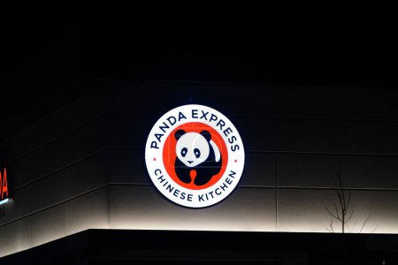 Foto de Oshkosh, Wisconsin, EE.UU. - 14 de abril de 2024: El letrero del logo de Panda Express brilla por la noche en el lado del edificio del restaurante. - Imagen libre de derechos