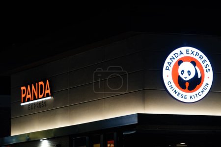 Foto de Oshkosh, Wisconsin, EE.UU. - 14 de abril de 2024: El letrero del logo de Panda Express brilla por la noche en el lado del edificio del restaurante. - Imagen libre de derechos