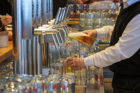 Foto de Un posadero llena vasos de cerveza en el bar del dispensador - Imagen libre de derechos