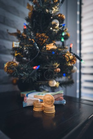 Foto de Debajo de un árbol de Navidad se encuentra un paquete de dinero en efectivo y una pila de monedas de oro Krugerrand - Imagen libre de derechos