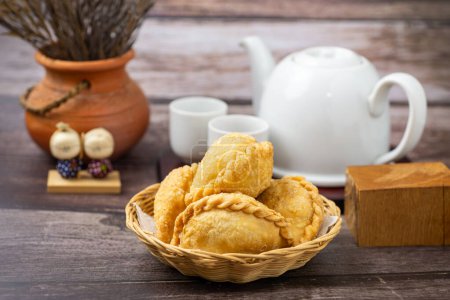 Curry puff, white teapot set isolated on white background. Samosa chicken fried curry bakery, meat, vegetable on wooden table. Yummy pie, Asian street food, Crispy snack eating with tea, coffee bread