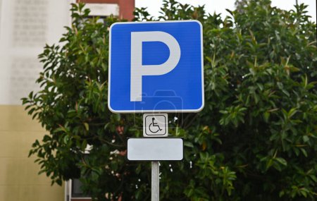Foto de Señal de tráfico de estacionamiento para discapacitados. Símbolo callejero con silla de ruedas. Lugar adicional para aparcar un coche para personas con discapacidad. Este lugar es la zona más accesible para aparcar un coche. - Imagen libre de derechos