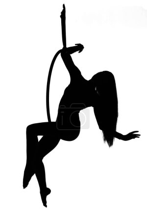 Foto de Silueta de bailarina aérea. Mujer o niña actuando en el aro. mujer trapecista sentado en un aro suspendido en el aire - Imagen libre de derechos