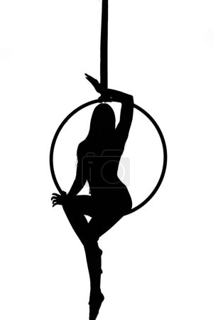 Foto de Silueta de bailarina aérea. Mujer o niña actuando en el aro. mujer trapecista sentado en un aro suspendido en el aire - Imagen libre de derechos
