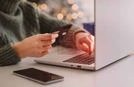 Photo for Christmas online shopping, sales and discounts promotions during winter holidays, online shopping at home. Female hands on the laptop with blurred bokeh lights. - Royalty Free Image