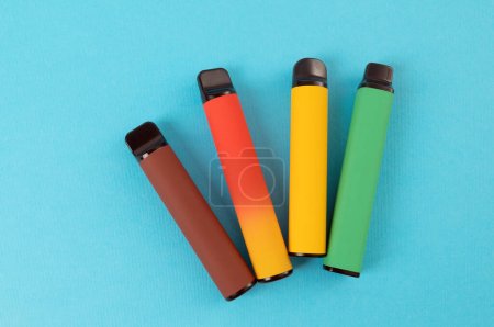 Téléchargez les photos : Set of colorful disposable electronic cigarettes on a blue background. The concept of modern smoking. Top view - en image libre de droit