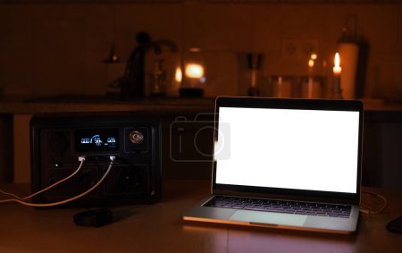 Photo for Charging station for laptop and desk lamp when there is no light during blackout. Generator power bank battery in the absence of electricity. at home table - Royalty Free Image