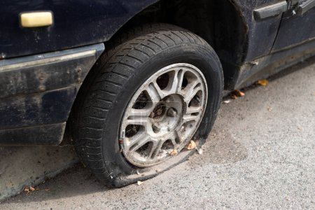 Nahaufnahme beschädigter Reifen. Das Rad des Autoreifens war undicht. Reifenplatzer wartet auf Reparatur. Verlassenes Auto auf dem Parkplatz.