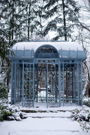 Foto de Un cenador de hierro de metal azul hecho de metal en un jardín de nieve en invierno. - Imagen libre de derechos